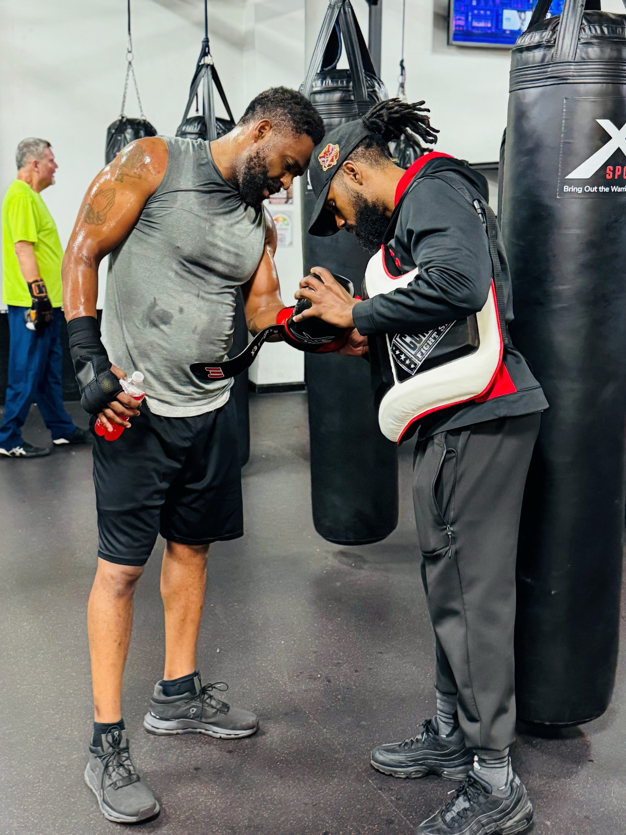 Coach CL training a client in a boxing gym